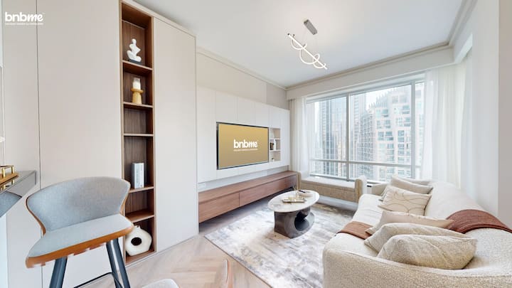 Entra en un espacio iluminado por el sol con ventanas del suelo al techo, un sofá de primera calidad, un elegante televisor inteligente y una decoración contemporánea. Perfecto para relajarse, transmitir o disfrutar de las vistas del horizonte del centro de Dubái, ideal para familias, parejas y trabajadores remotos.