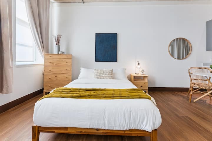 Ეს საძინებელი ნათელი და მიმზიდველია ხრაშუნა თეთრ თეთრეულში გამოწყობილი კომფორტული ორადგილიანი საწოლით და მდოგვის აქცენტით. Ბუნებრივი სინათლე ჩნდება მაღალი ფანჯრებიდან, ხოლო მინიმალისტური ხის ავეჯი და თანამედროვე დეკორი ქმნის მშვიდ, ელეგანტურ დასვენებას.