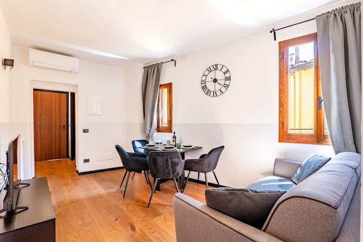 Amplia sala de estar luminosa con grandes ventanales, TV inteligente y cómodo sofá cama (190x140 cm) para huéspedes adicionales. Incluye una gran mesa para 4 personas, ideal para relajarse y compartir momentos especiales juntos, y aire acondicionado.