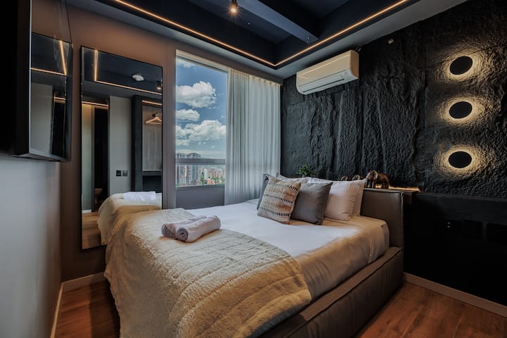 Amplio dormitorio secundario con una lujosa cama tamaño queen, una decoración refinada y un ambiente sereno. Perfectamente diseñada para combinar comodidad y estilo, ofrece un refugio relajante después de un día explorando la vibrante ciudad.