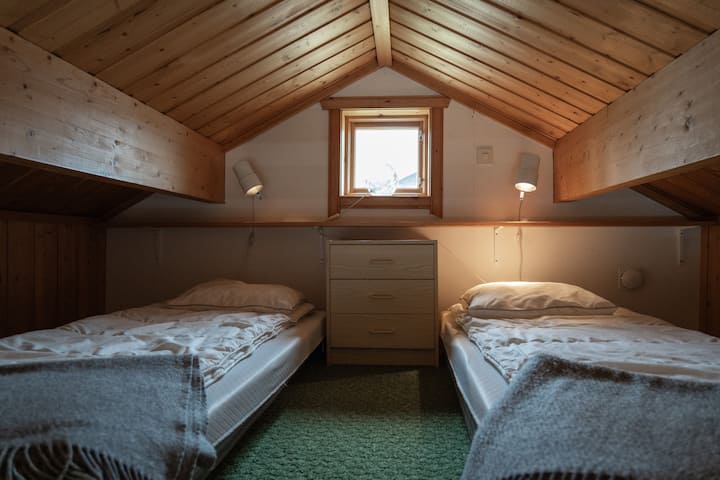 Sovloft med två enkelmadrasser och begränsad takhöjd.