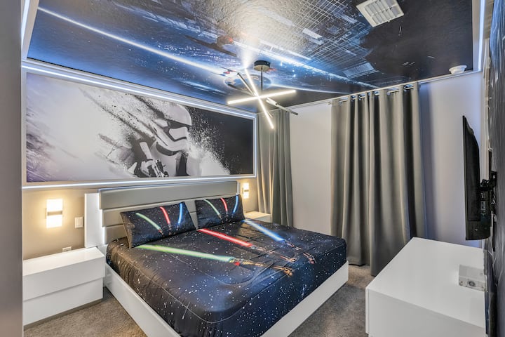 Évadez-vous dans une galaxie lointaine : lit plateforme avec literie sabre laser, fresque murale de stormtrooper et plafond de vaisseau spatial enveloppé d'une lueur DEL fraîche et de rideaux gris élégants, où chaque nuit se transforme en une aventure épique à la vitesse de la lumière.                        