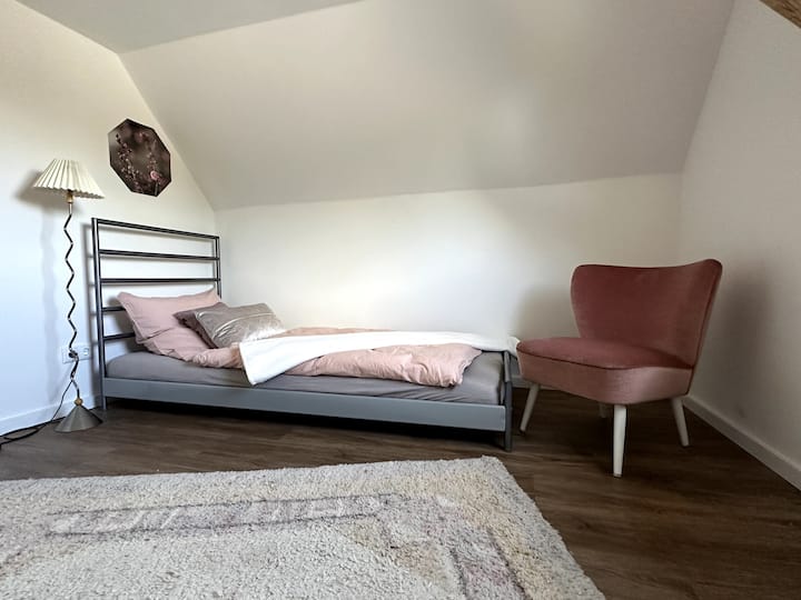 „Dein Logenplatz mit Koppelblick: Im Schmetterlingszimmer ist der Name Programm. Zwischen gemütlichen Holzbalken und zartem Rosé findest du absolute Entspannung. Ein Blick aus dem Fenster zu den Pferden genügt, um den Alltag sofort zu vergessen.“