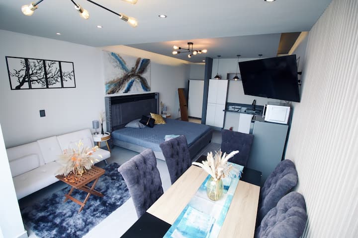 Chumba kizuri chenye kitanda cha ukubwa wa kifalme, chumba cha kulia chakula, sofa, televisheni mahiri (akaunti za kutazama mtandaoni ni kwa gharama ya mgeni), jiko, friji, mikrowevu, kabati la nguo, bafu la kujitegemea, miongoni mwa vistawishi vingine.