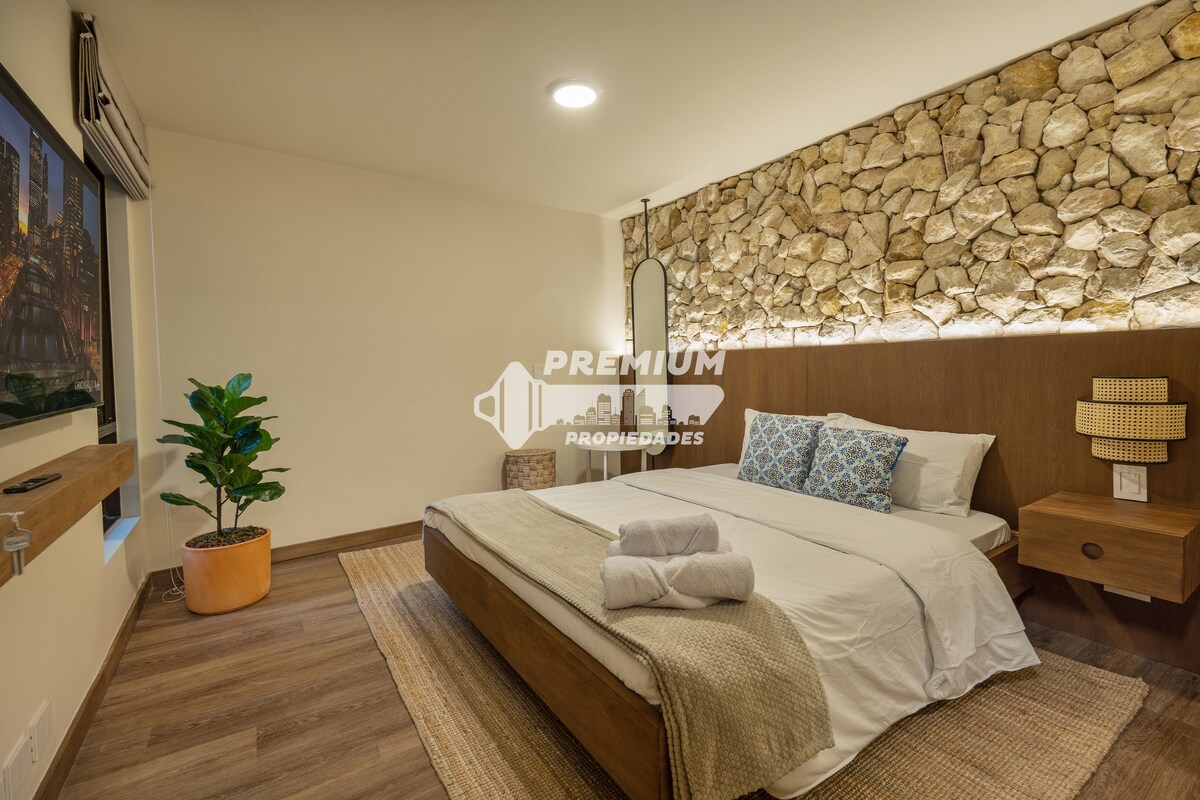 Стилна втора спалня с текстурирана каменна акцентна стена, модерно осветление и уютно спално бельо за спокойна атмосфера