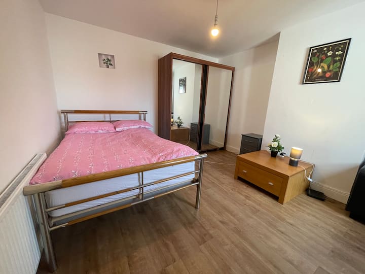 Dormitorio doble principal con un armario de lujo, dos zonas de almacenamiento, una flor, un sofá y calefacción central con balcón.    