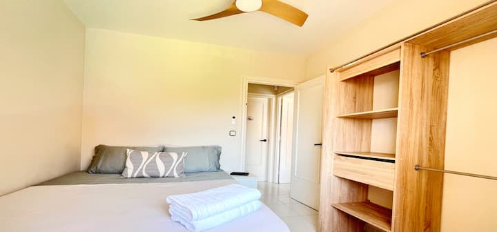 La seconda camera da letto ha un letto matrimoniale, un ventilatore a soffitto e un pratico armadio in legno aperto. Il suo design semplice e luminoso crea un'atmosfera rilassante per un sonno confortevole.