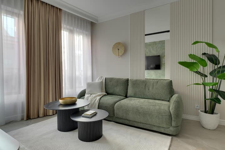 Пространа и светла дневна соба со удобен кауч на спуштање и телевизор, совршена за вечерна релаксација. Големите прозорци пропуштаат многу природна светлина, создавајќи пријатна атмосфера.