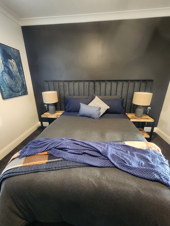 Tmavomodré tóny, luxusné čelo postele a manželská posteľ značky Sealy zaručujú pokojnú noc.