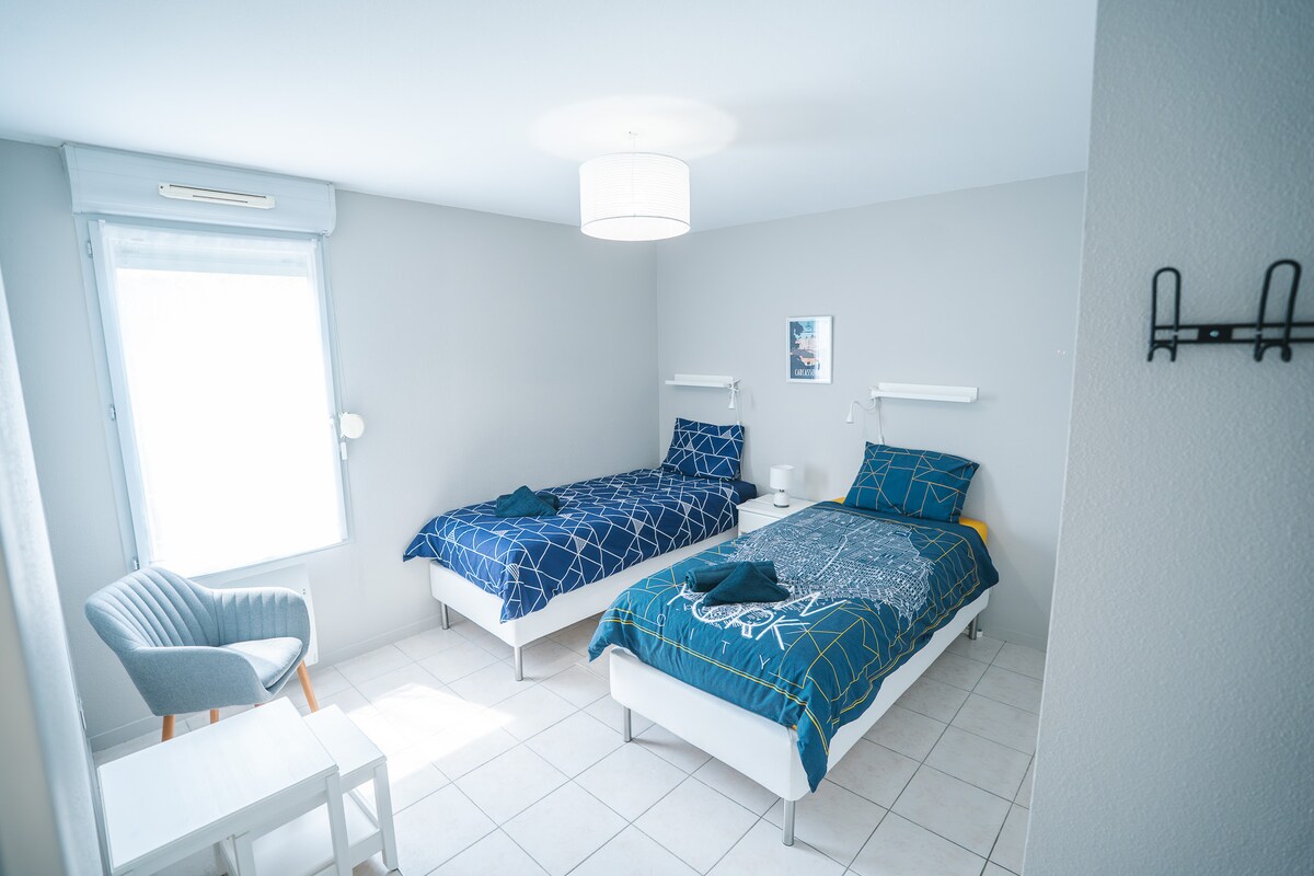 ห้องนอนมีเตียงเดี่ยวสองเตียง ชั้นวางโคมไฟข้างเตียง และตู้เก็บของ 