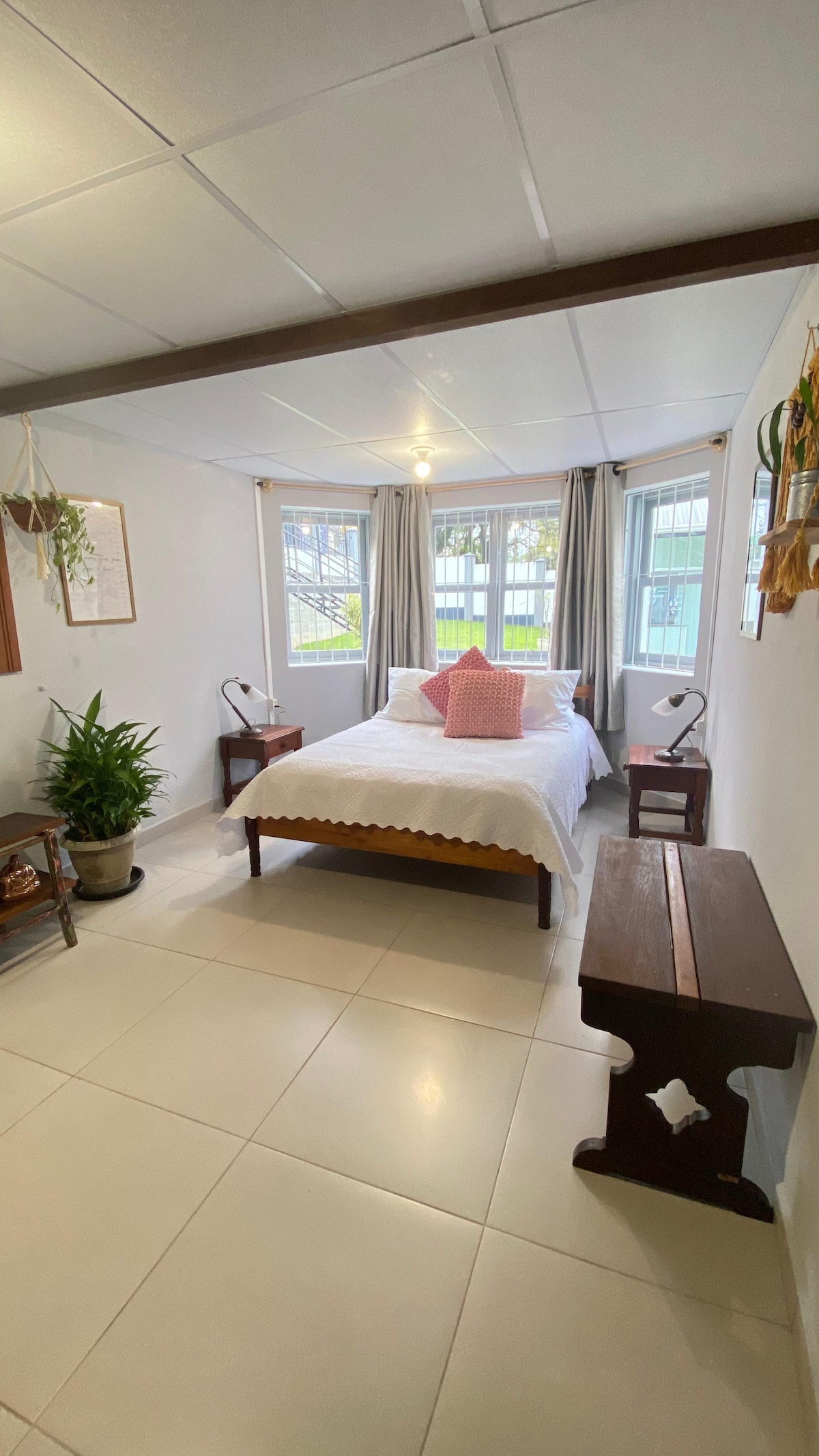 Luminosa y acogedora con una cama doble, grandes ventanales y cortinas. Decoración limpia con toques de madera y plantas, creando un refugio tranquilo y acogedor. Perfecto para relajarse y recargar energías. Disfruta de un ambiente sereno y cómodo