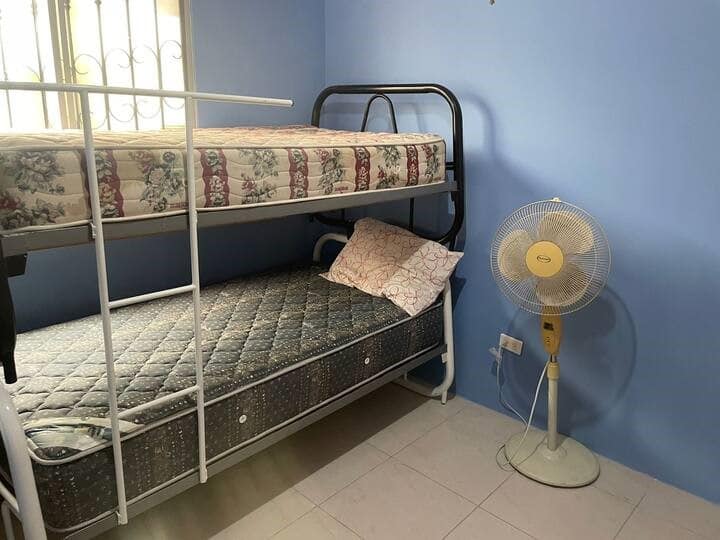 一张全尺寸双层床，配有枕头和床单、风扇和衣柜，可存放衣服