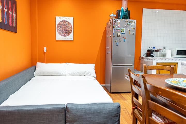 Cucina open space moderna e accogliente, collegata alla zona living con divano letto aperto in modalità letto, creando un ambiente funzionale e confortevole ideale per il relax e il riposo degli ospiti.