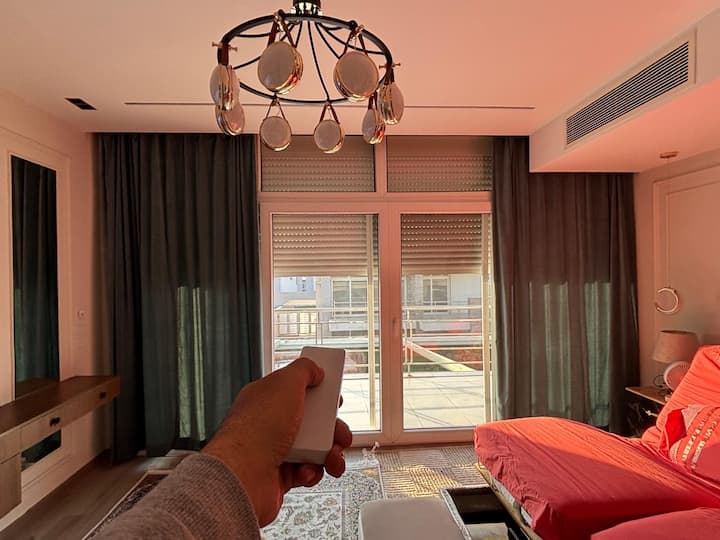 Pametne zavjese na daljinsko upravljanje u glavnoj spavaćoj sobi. Također su prikazane motorizirane, oklopljene rolete za zamračenje (više od 90 % vrata i prozora vile pokriveno je ovim roletama). Primijetite podesivi krevet, skriveni ventilacijski otvor za klima-uređaj i još mnogo toga