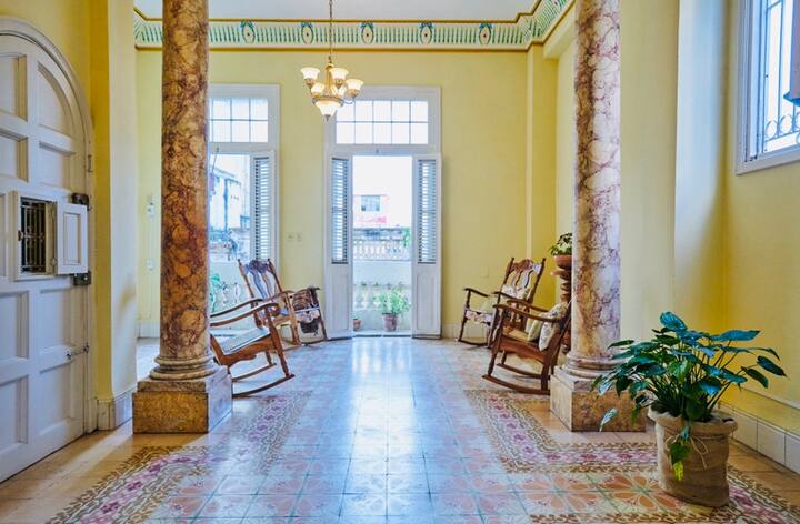 Salón neocolonial luminoso y espacioso con balcón con vistas a la bulliciosa calle de La Habana Vieja