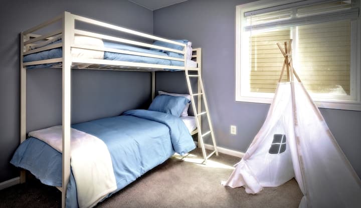 una habitación con literas para niños o grupos: un espacio alegre y acogedor con una litera doble, una decoración divertida y un pequeño rincón tipi para que los más pequeños se relajen o jueguen. Perfecto para familias o amigos que comparten la estancia