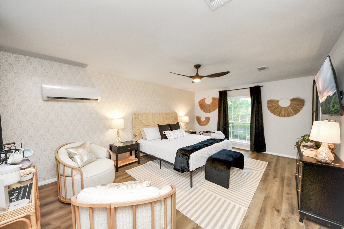 غرفة نوم رئيسية في الطابق السفلي كاملة مع سرير بحجم كينج ومنطقة جلوس وعربة قهوة وحمام داخلي.