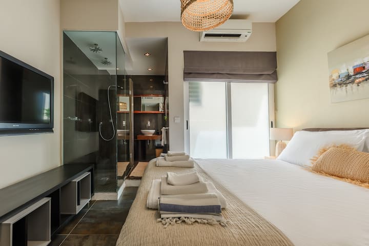 Otro ángulo de un dormitorio doble elegante y luminoso con cama tamaño queen y baño privado. 