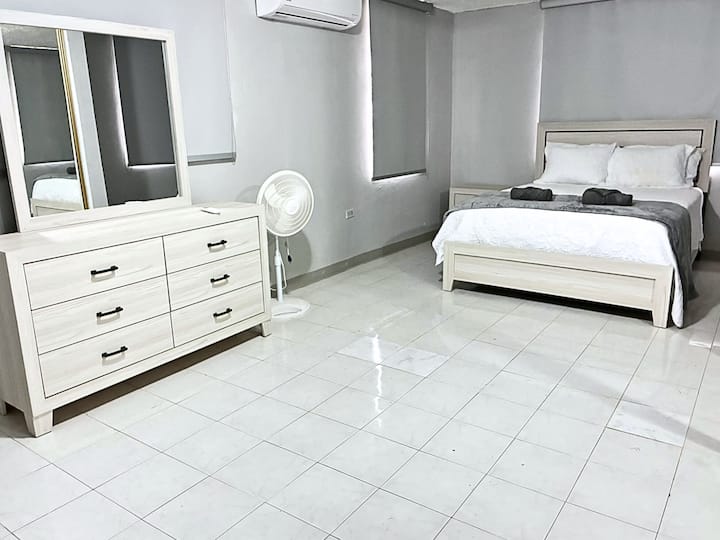 Amplio dormitorio con cama tamaño queen, vestidor, aire acondicionado y decoración moderna.