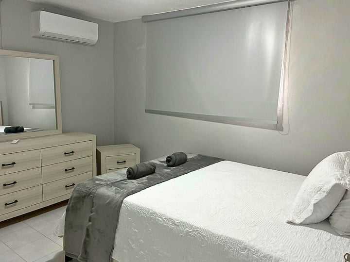 Acogedor dormitorio con una cama tamaño queen, espacio en el armario y muebles modernos para noches de descanso.