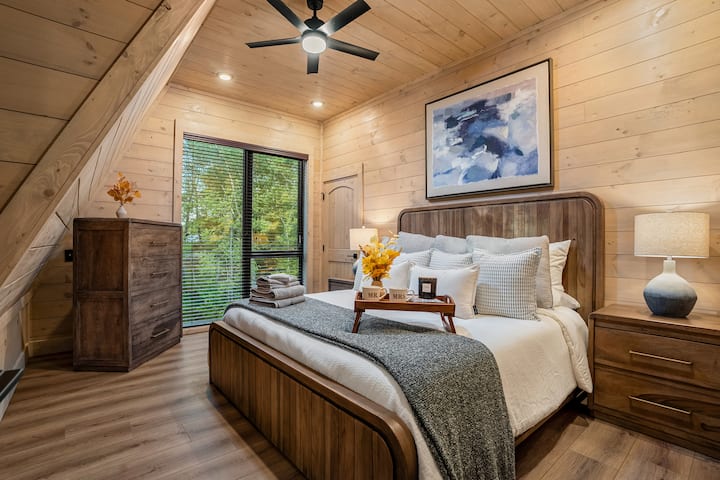 Charming king bedroom with warm wood finishes and peaceful forest views.