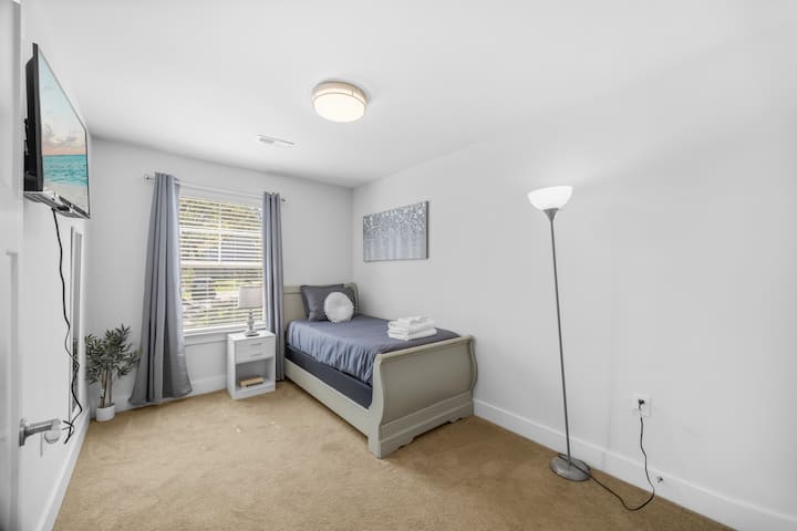 Ein gemütliches Einzelbett mit frischer Bettwäsche, natürlichem Licht und beruhigender Einrichtung macht dieses Zimmer ideal zum Entspannen.