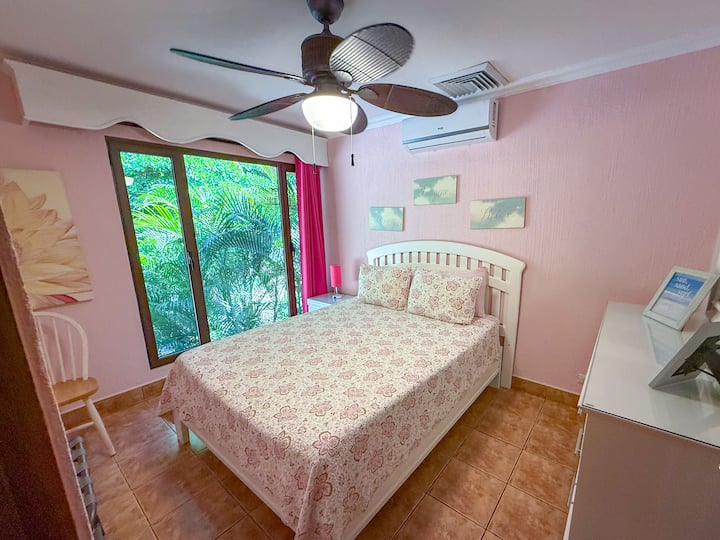 חדר אורחים מקסים עם מצעים פרחוניים, נוף לגינה וגווני ורוד עדינים – מושלם לבוקרים שלווים ולילות מרגיעים.