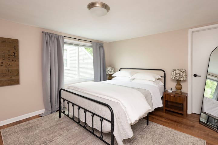 Este dormitorio en el segundo piso tiene una sensación tan relajante, con tonos de madera natural y hermosos grises. Esta habitación tiene un espejo de cuerpo entero, un hermoso tocador reformado y un ventilador portátil para tu comodidad. 