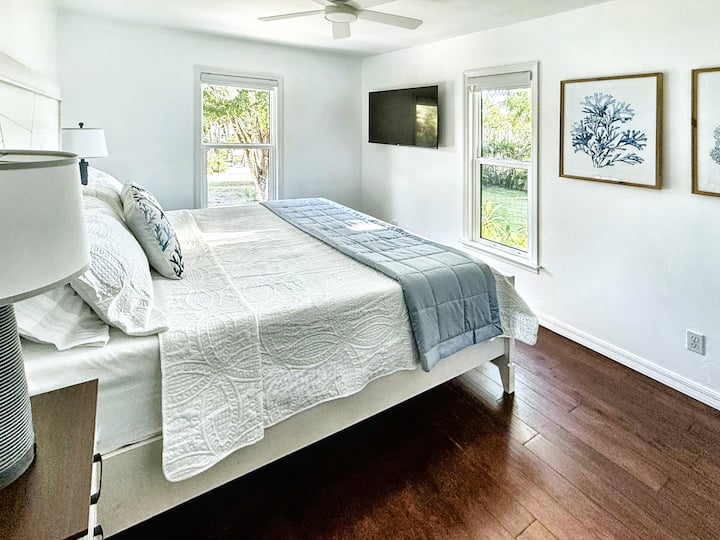 Dormitorio luminoso y apacible con una cama tamaño king, una suave decoración de estilo costero y abundante luz natural, perfecto para una estancia relajante y cómoda.