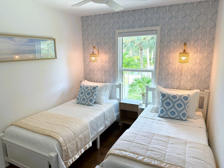 Encantador dormitorio doble con dos camas cómodas, una suave decoración de estilo costero y un ambiente luminoso y acogedor, perfecto para niños o huéspedes adicionales.