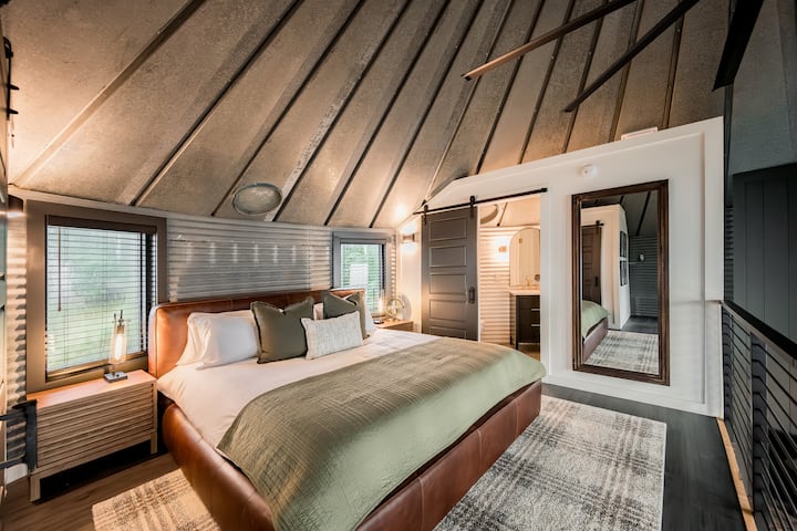 Upstairs loft with king bed + full bathroom. *FYI: the bathroom ceiling is open to the main space. For extra privacy, please use the fan and the provided freshening spray.