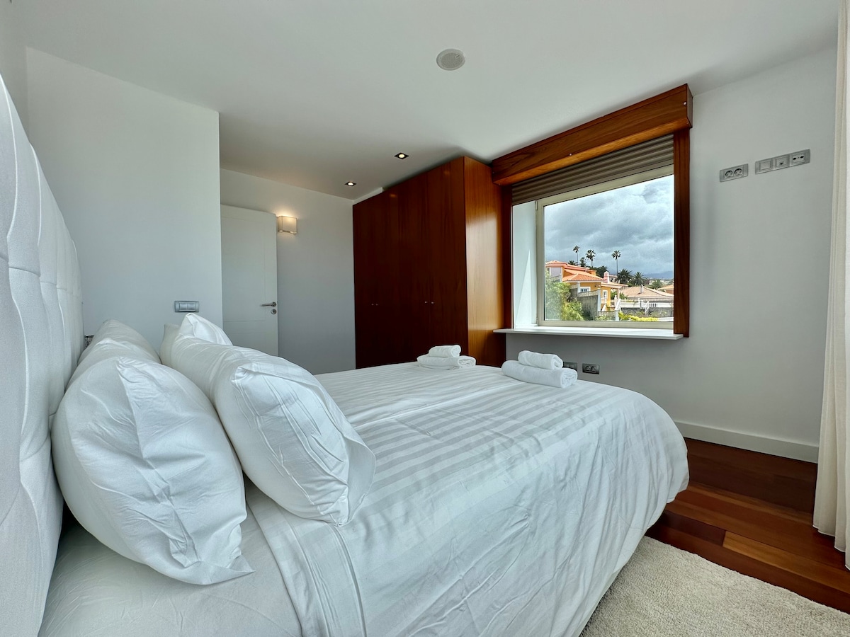 спалня с двойно легло и с големи прозорци и хубави гледки