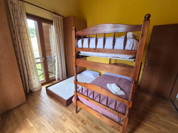 Спална соба за тројца, со пристап до мал балкон со поглед на планина.