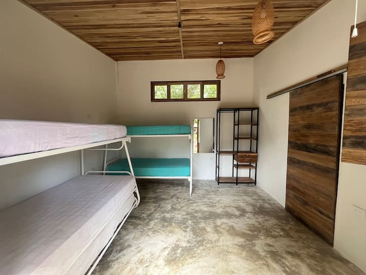Habitación 2. Amplia, con techo de madera y camarotes cómodos. Con 2 muebles abiertos de metal y madera que combinan con estilo rústico y funcionalidad, ideales para organizar pertenencias y mantener un ambiente ordenado y acogedor. 