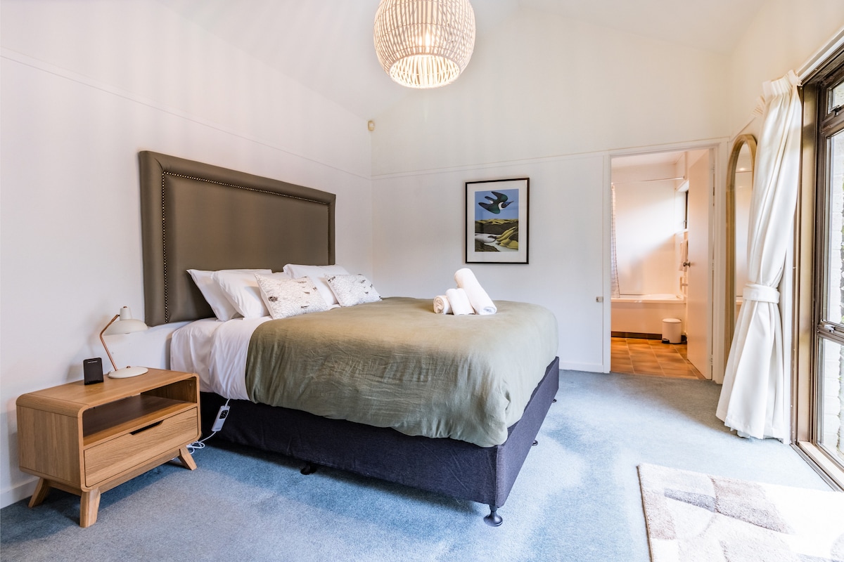 The master bedroom features a plush king bed, local NZ artwork, and a sliding door that opens straight onto the patio — perfect for morning coffees or starry nights. Includes a private ensuite for that extra touch of comfort.