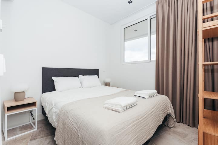 Dieses gemütliche Schlafzimmer ist einfach, aber ruhig und kombiniert sanfte Erdtöne mit klaren Linien und natürlichem Licht. Es bietet ein erholsames Ambiente, ideal zum Entspannen in ruhigem, modernem Komfort.