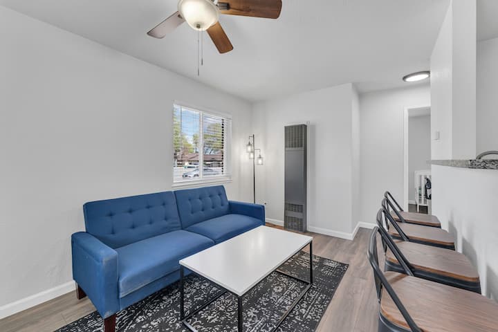 Relájate con comodidad en la audaz sección azul, frente a un telón de fondo elegante y moderno con paredes blancas brillantes, suelos de madera y abundante luz natural, perfecto para relajarse después de un día de exploración.