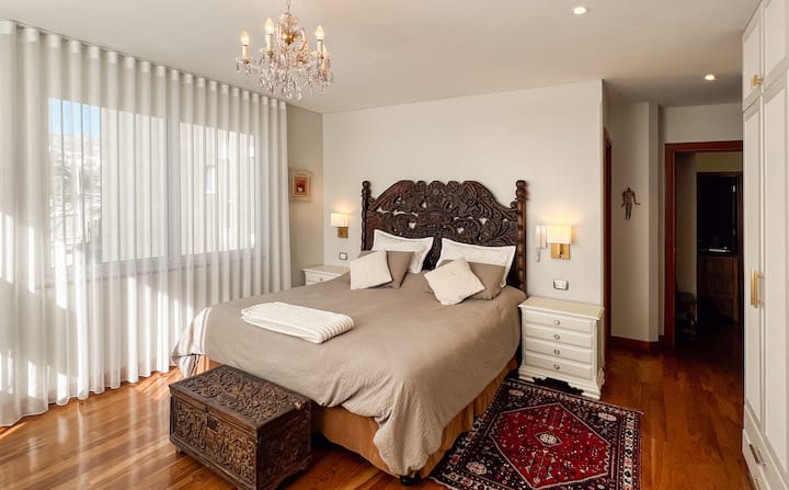 El cabecero de madera antigua y las sábanas de algodón egipcio de lujo te invitan a sumergirte en un sueño reparador. Las mesitas de noche de diseño elegante ofrecen un generoso espacio de almacenamiento.  Cortinas transparentes y persianas opacas.