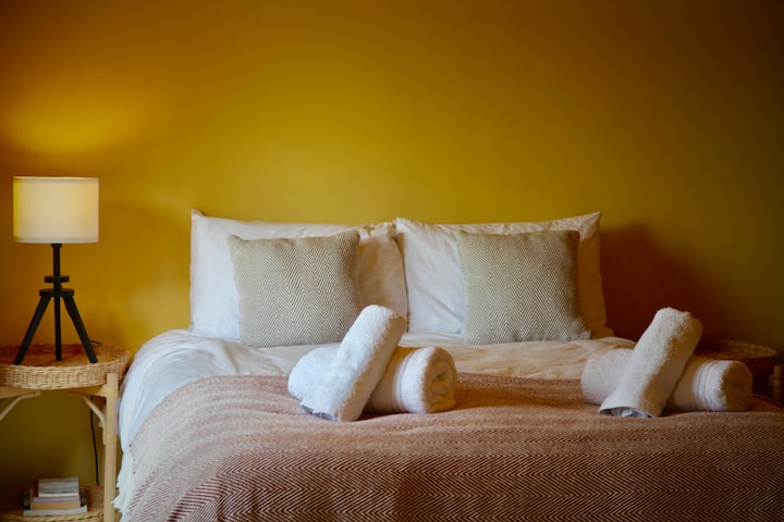 Dormitorio tamaño king con tonos tranquilos y puertas francesas que conducen al jardín.