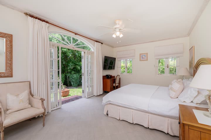 英国のキングサイズベッド、テレビ、庭につながるフレンチドア、専用バスルームを備えた静かな寝室2。  