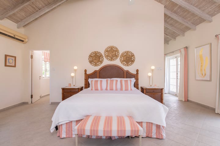 英国のキングサイズのベッド、テレビ、バルコニー、ウォークインクローゼット、専用バスルームを備えた素晴らしいマスターベッドルーム。  