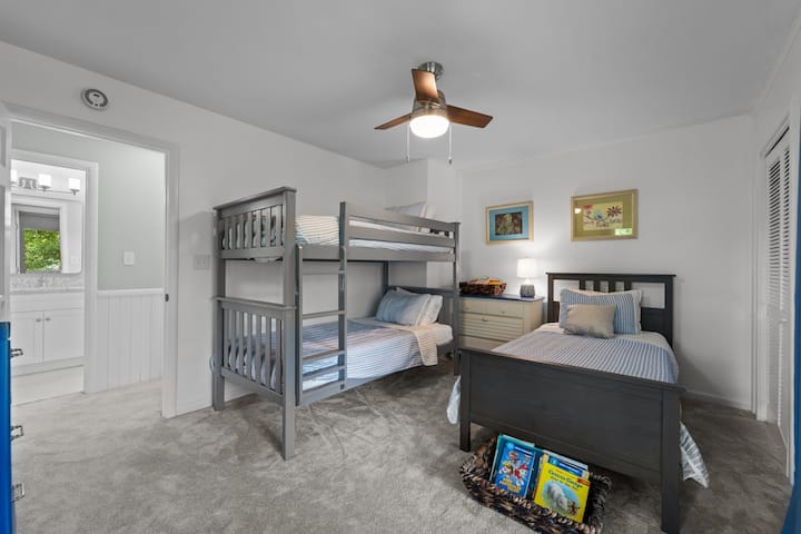 Cette chambre dispose de 3 lits simples, dont 1 lit superposé. Vous trouverez aussi une table de hockey sur coussin d'air et des livres pour enfants. Toutes les chambres ont accès à des terrasses extérieures.