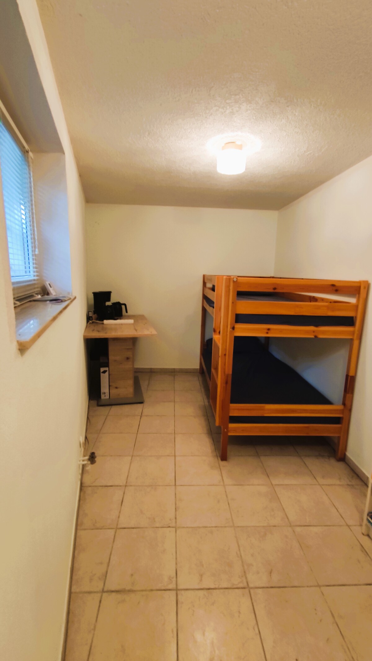 Spavaća soba s krevetom na kat i aparatom za kavu.