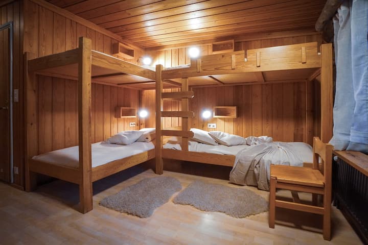 Varm och inbjudande sovplats med robusta 100 cm breda våningssängar, mjuk belysning och naturlig träomgivning – ett mysigt och säkert utrymme för barn eller vänner att vila och ladda upp.