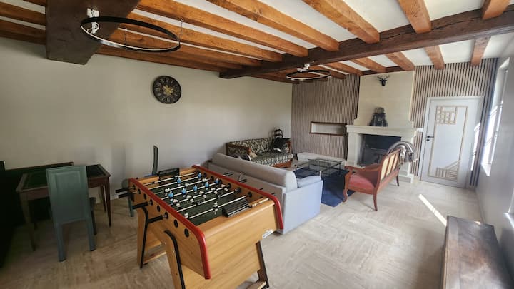 Vista desde el salón principal con futbolín, sofá, mesas de juego, chimenea...