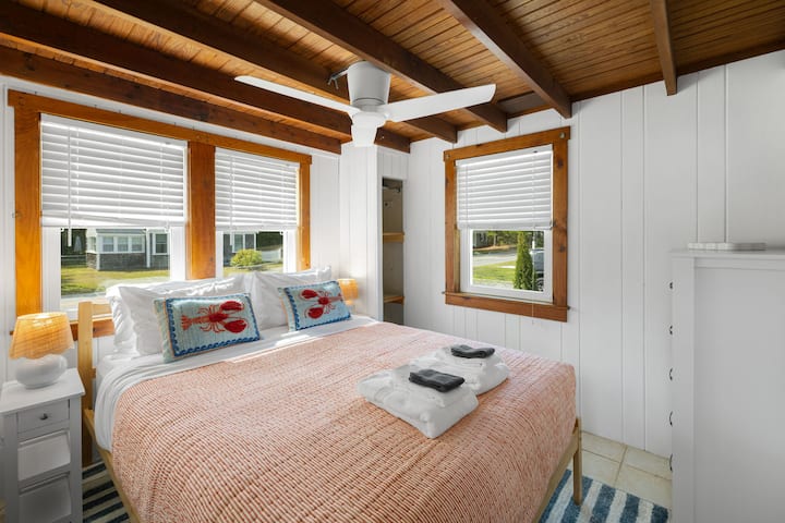 Relájate en esta habitación con una cama tamaño queen, completa con encantadores cojines decorativos de langosta y sábanas de color salmón para un toque de estilo costero.