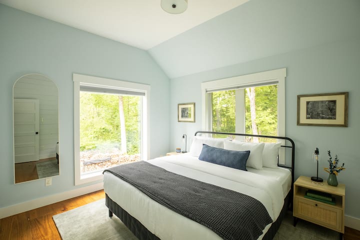 King bedroom with picture windows and forest views. Start the day with light streaming in from two sides.