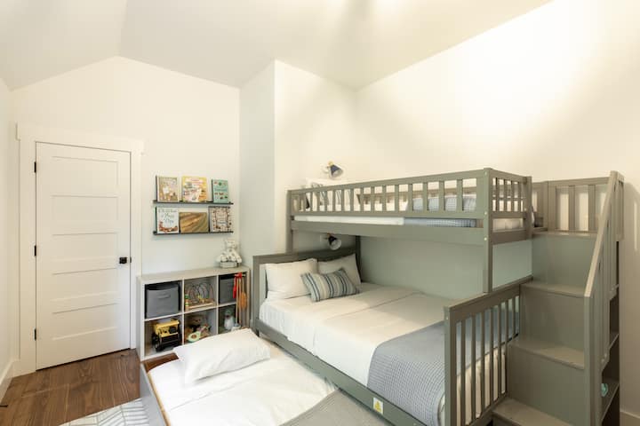 Kid-friendly bunk room with full-size bed, twin upper bunk, and pull-out trundle. Perfect for sleepovers or families.