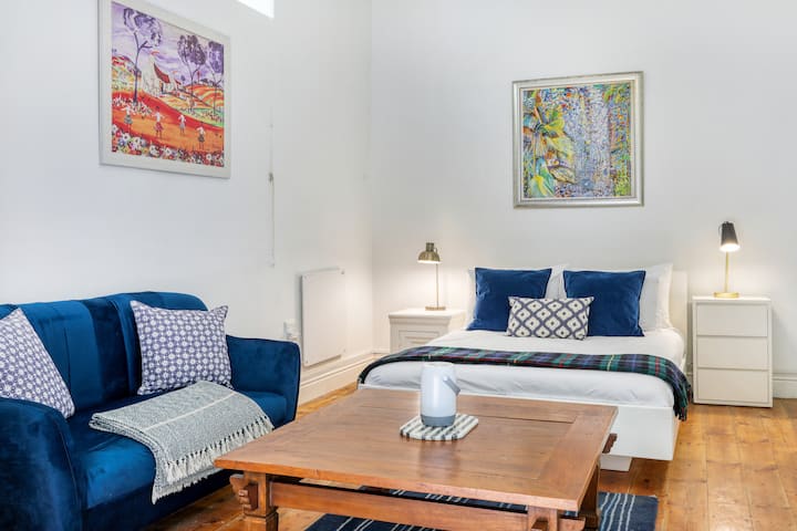 单间公寓区，配有舒适的床、沙发和壁挂式暖气。