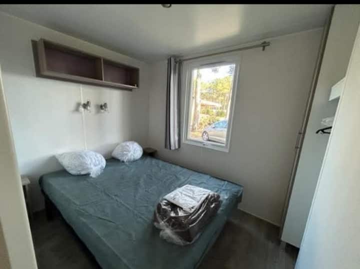 سرير مزدوج في غرفة النوم مع خزانة تخزين وخزانة ملابس جانبية مع طاولتين صغيرتين بجانب السرير